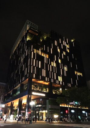 Un bâtiment moderne à la façade originale, caractérisée par des bandes lumineuses verticales et un hall d’entrée en verre.