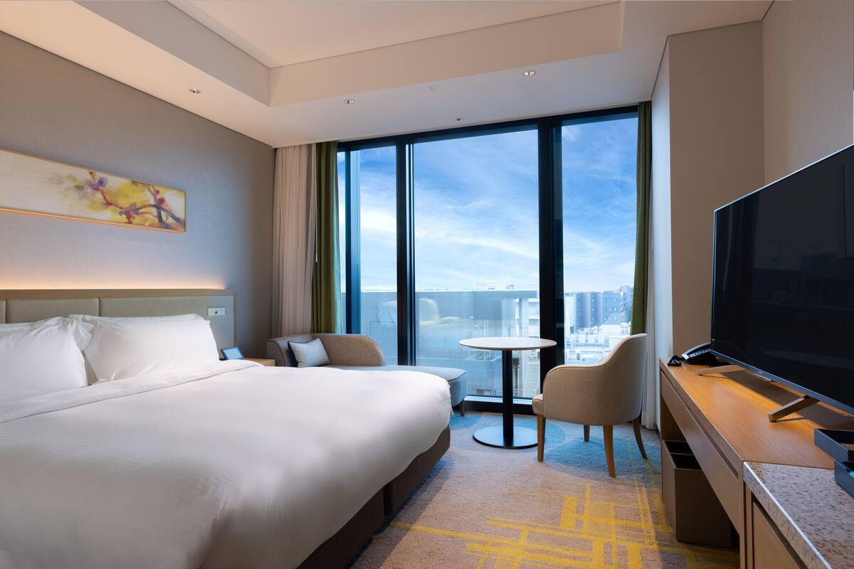 Une chambre d’hôtel moderne avec un grand lit, une télévision, une petite table et une chaise.