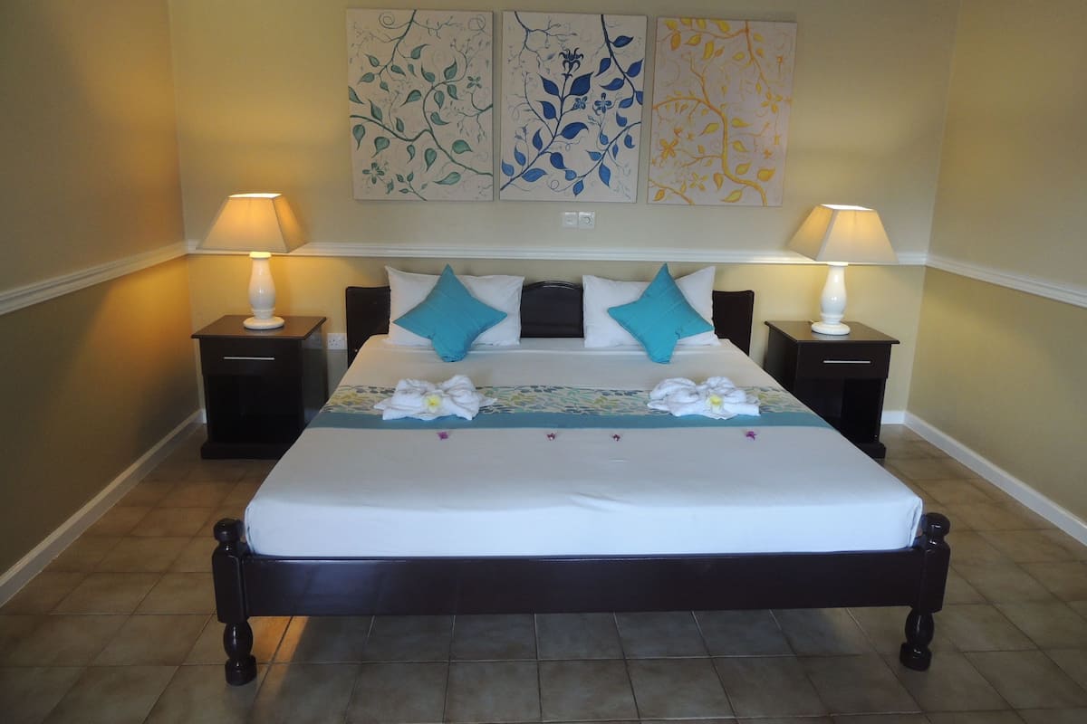 A neatly made bed with a floral bedspread, two nightstands with lamps, and three wall art pieces above the bed.