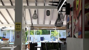 Un espace patio intérieur agrémenté de luminaires suspendus, d’une piscine, de coins salon extérieurs et offrant une vue sur la piscine.