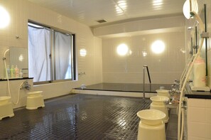 A bathroom with a large bathtub, multiple sinks, and a window. - Hotel Maruchu Classico (Tokyo)