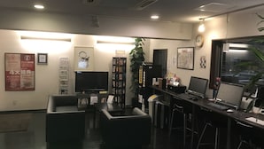 A modern office with a reception area, seating, a large flat-screen TV, a bookshelf, and a computer station. - Hotel Maruchu Classico (Tokyo)