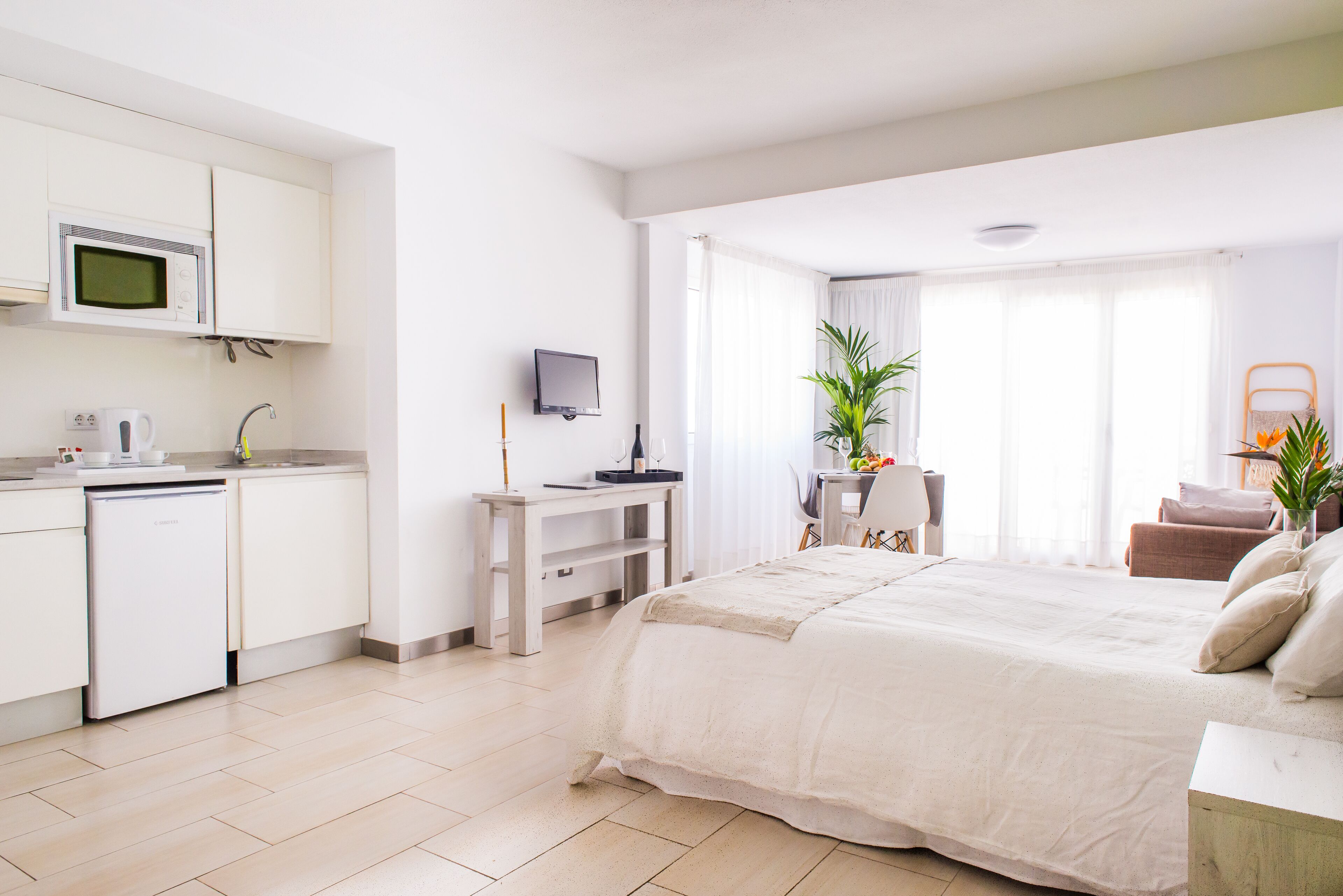 Habitación de hotel moderna con kitchenette, cama, escritorio y comedor.