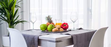 A dining table with a fruit plate, two glasses, and a pitcher of juice.
