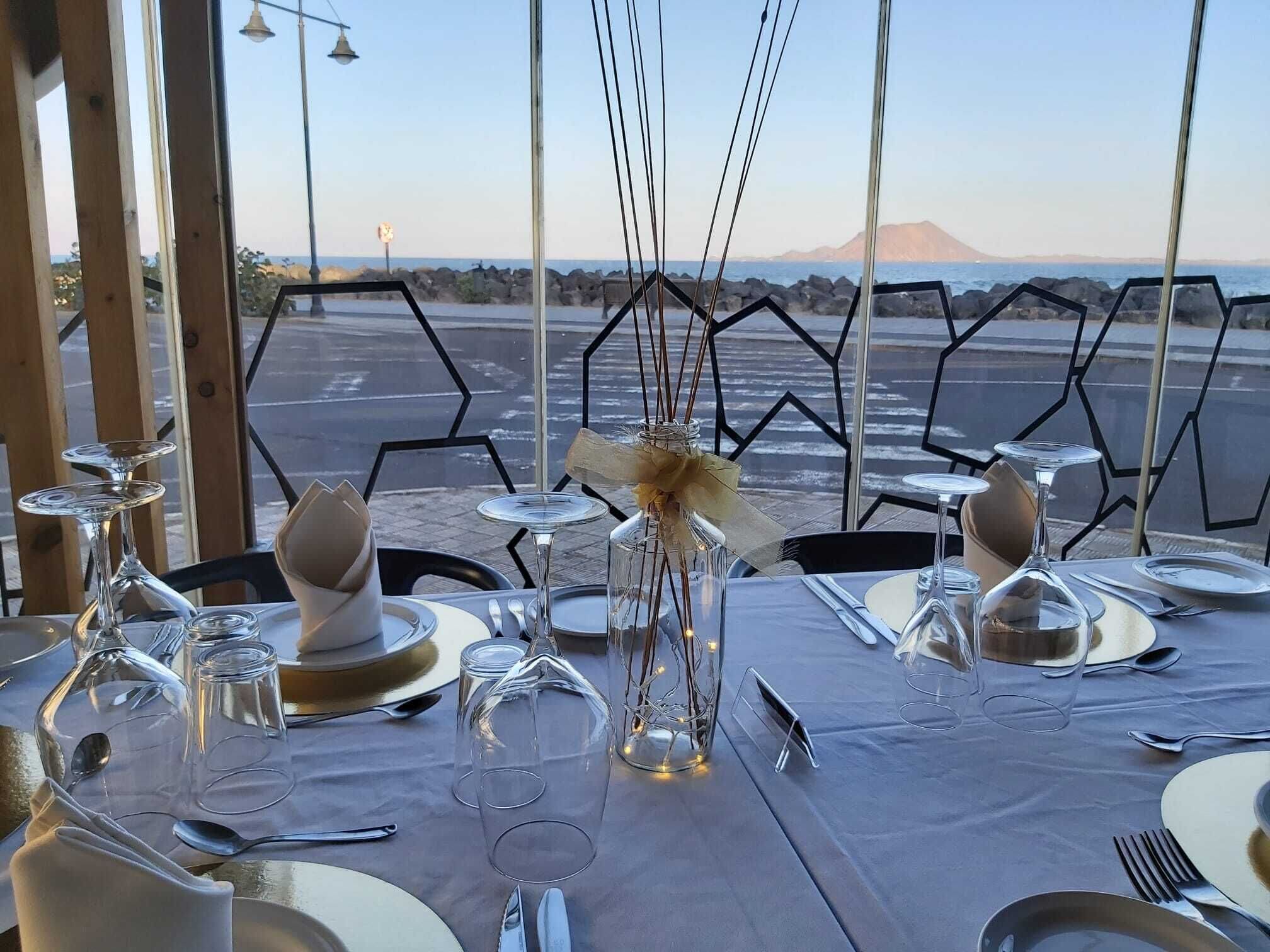 A table set for dining with a view of the ocean and a mountain in the background.