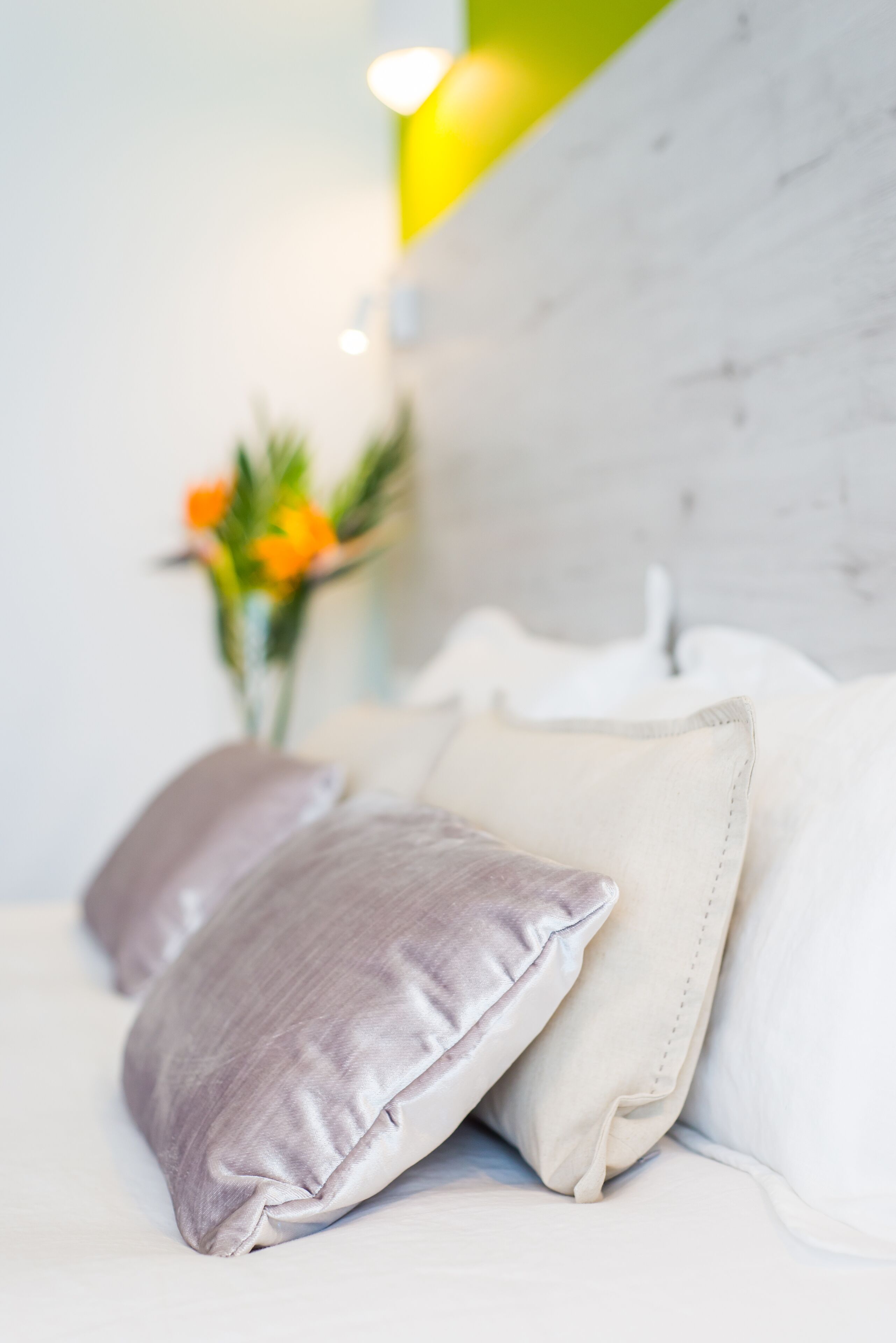A bed with pillows and a wall-mounted light fixture.