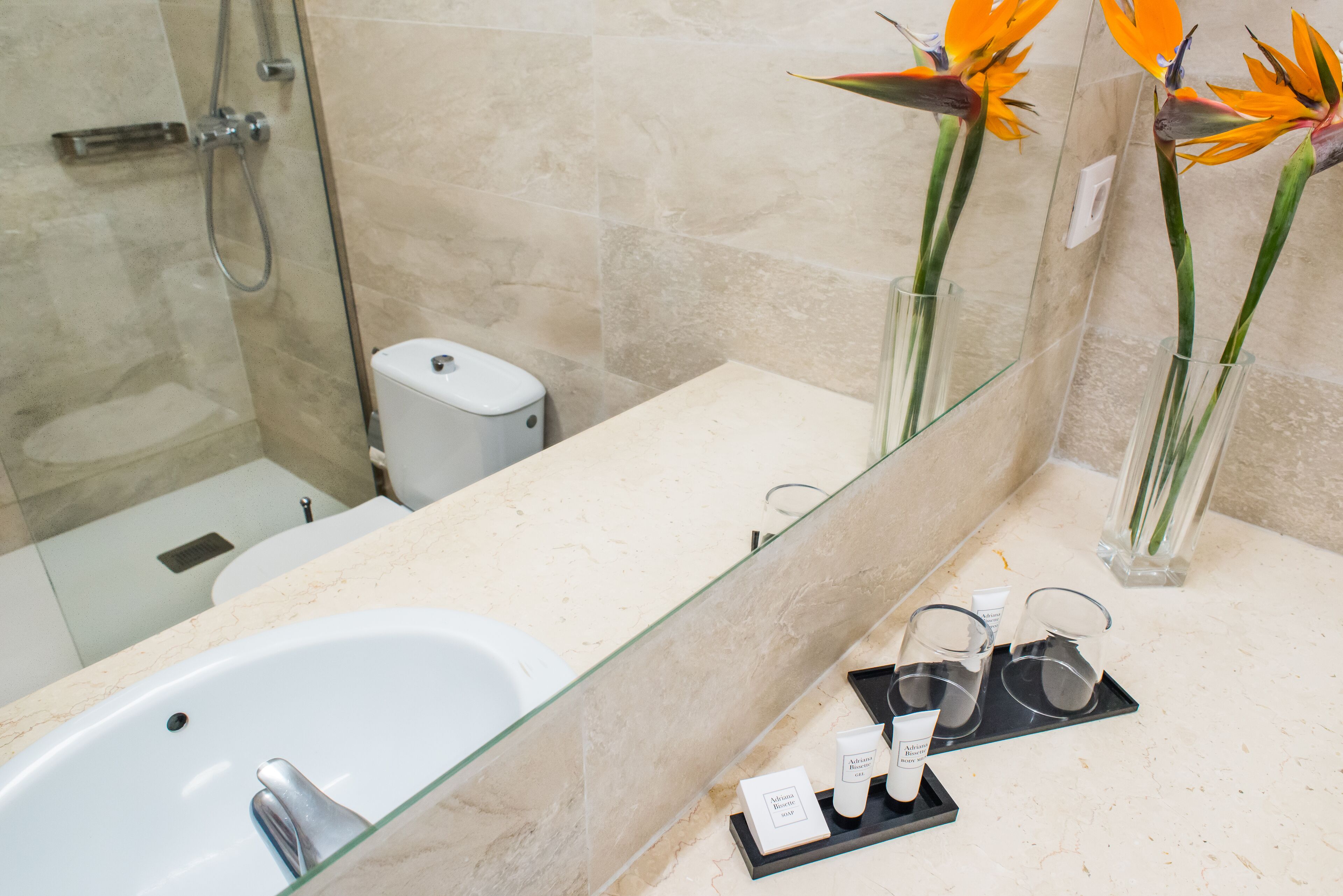 A modern bathroom with a glass-enclosed shower, a white sink, and a vanity with a mirror.