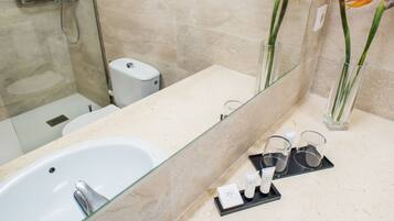 A modern bathroom with a glass-enclosed shower, a white sink, and a vanity with a mirror.