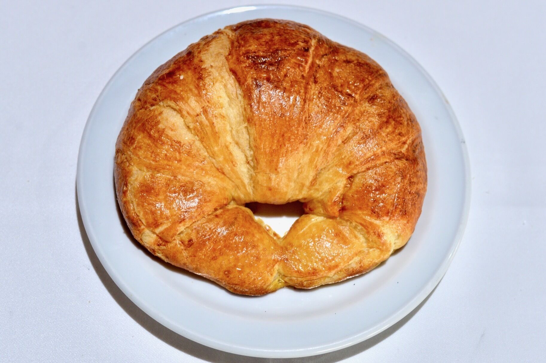 Une pâtisserie ronde, de couleur brun doré, posée sur une assiette blanche.