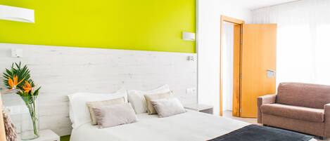 A hotel room with a bed, a nightstand, a chair, and a bright green accent wall.