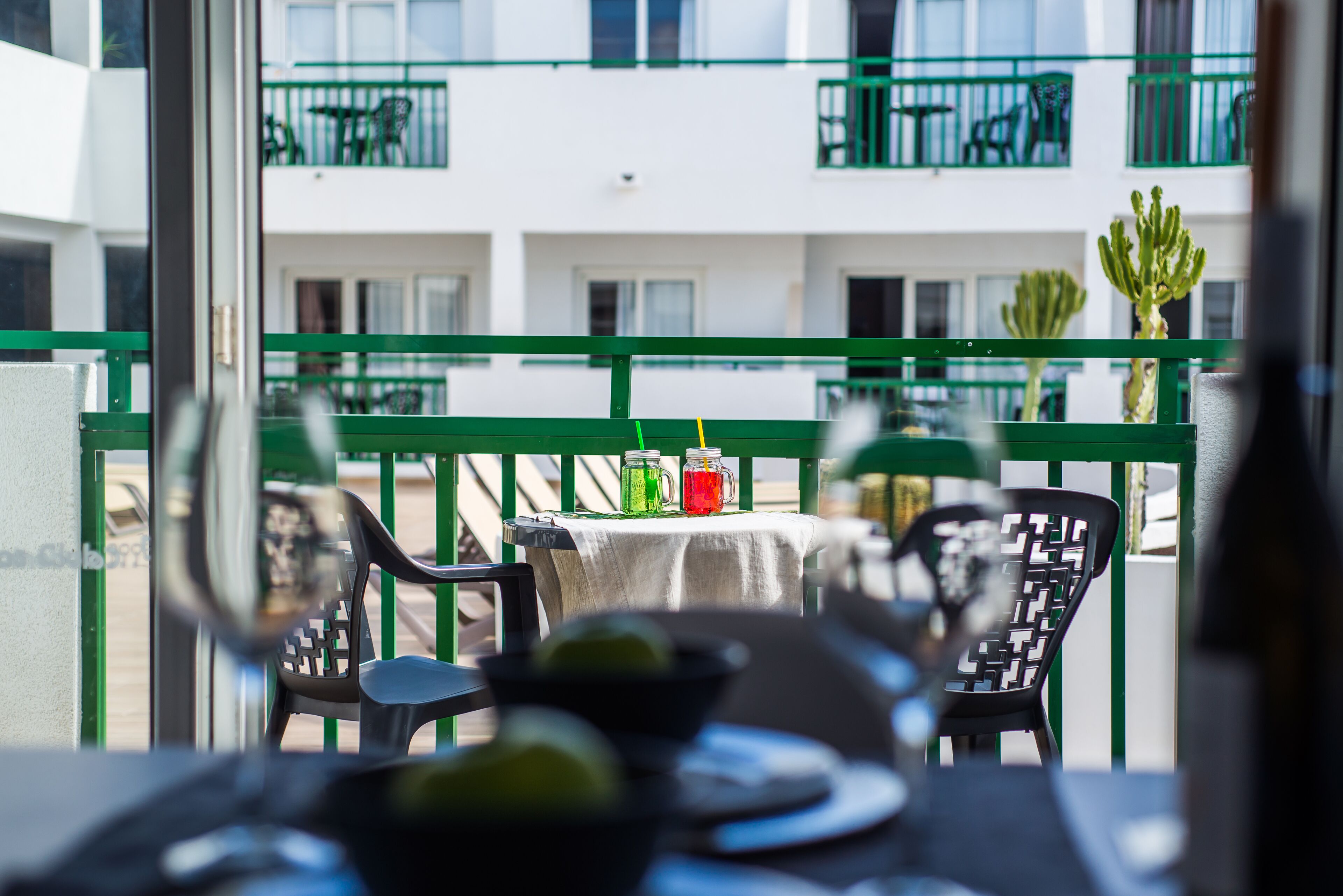 A balcony with a table, chairs, and a cactus.