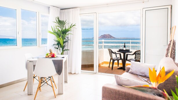 A balcony with a table and chairs, a sofa, and a potted plant. - Apartamentos Dunas Club (La Oliva)