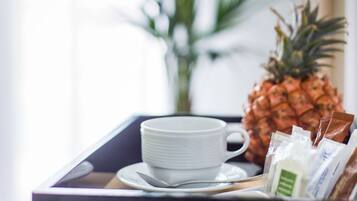 Una bandeja con una taza blanca, una piña y algunos productos envasados, probablemente desayuno.