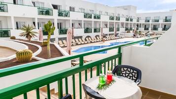 Zona de piscina con tumbonas, una mesa con bebidas y una planta de cactus.