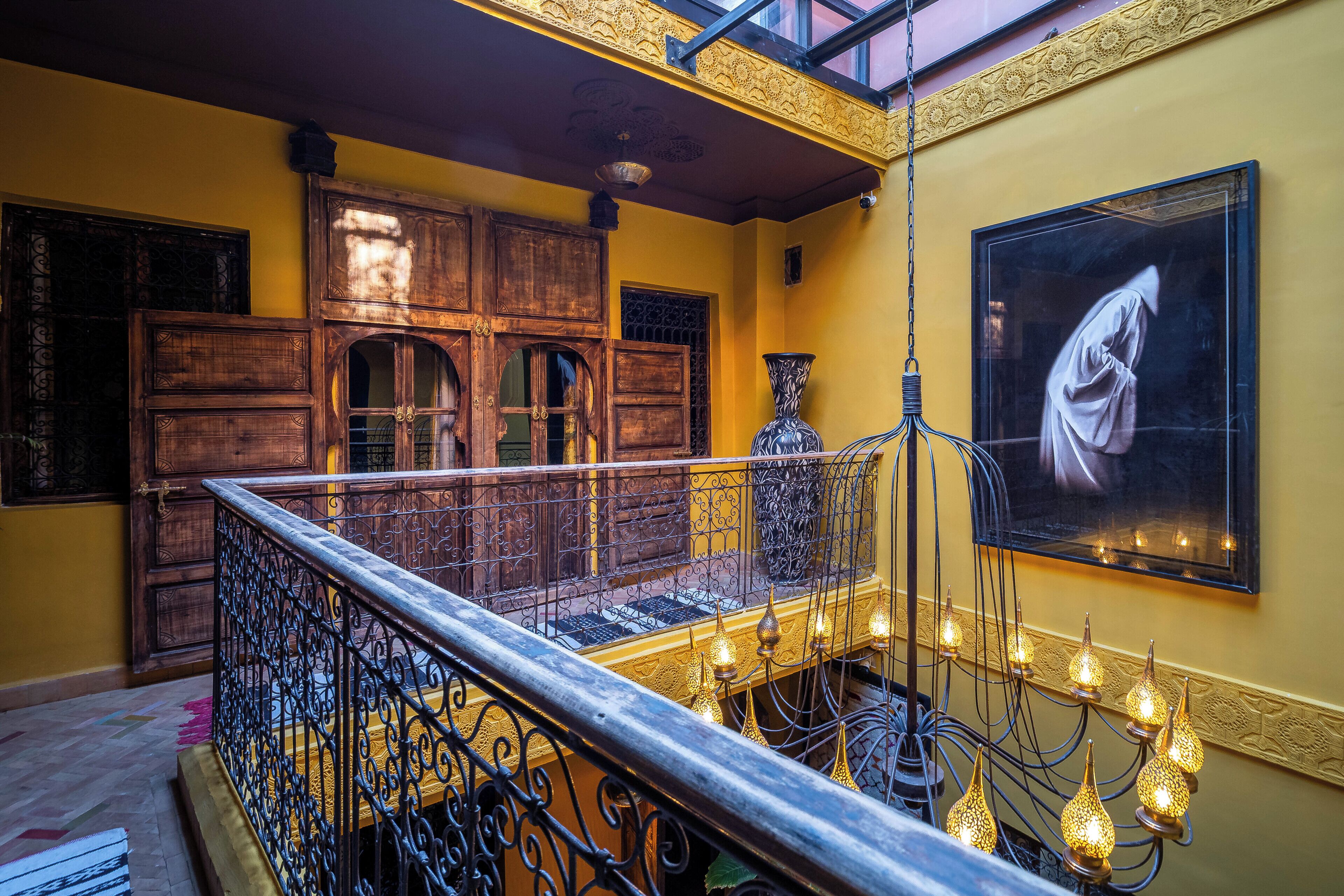 Una escalera con barandillas ornamentales, una puerta de madera y una obra de arte grande enmarcada en la pared.