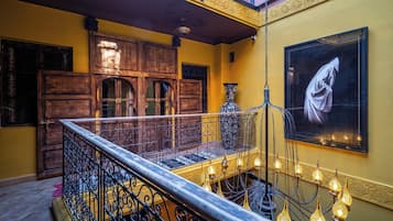 Una escalera con barandillas ornamentales, una puerta de madera y una obra de arte grande enmarcada en la pared.