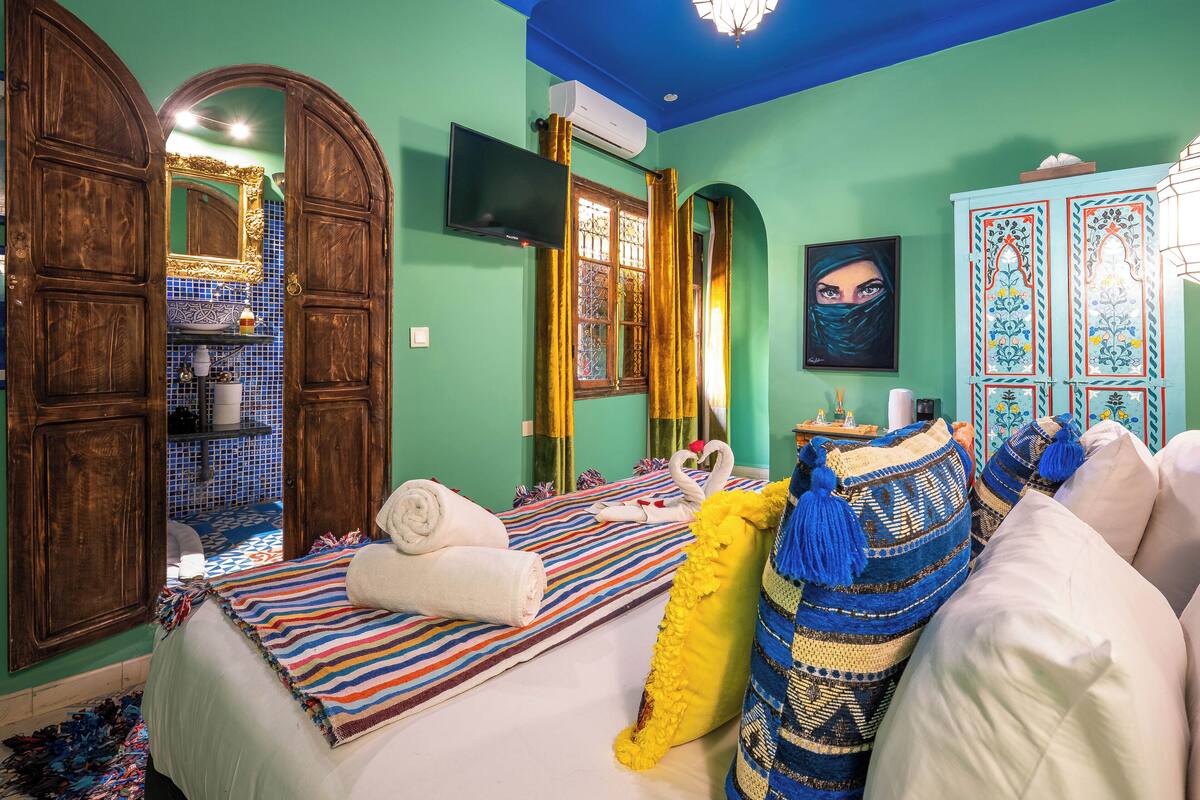 A room with a bed, a TV, a mirror, and a wardrobe.