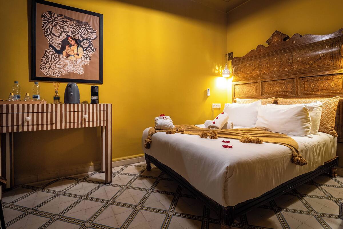 A hotel room with a bed, a bedside table, a wall-mounted artwork, and a patterned floor.