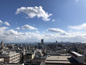 Une vue urbaine présentant une variété de bâtiments, notamment des immeubles de grande hauteur et des constructions plus basses, sous un ciel partiellement nuageux.
