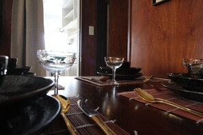 A dining table set with plates, bowls, and cutlery, with a view of a window and a door in the background. - Sea View Court Kobe (Kobe)
