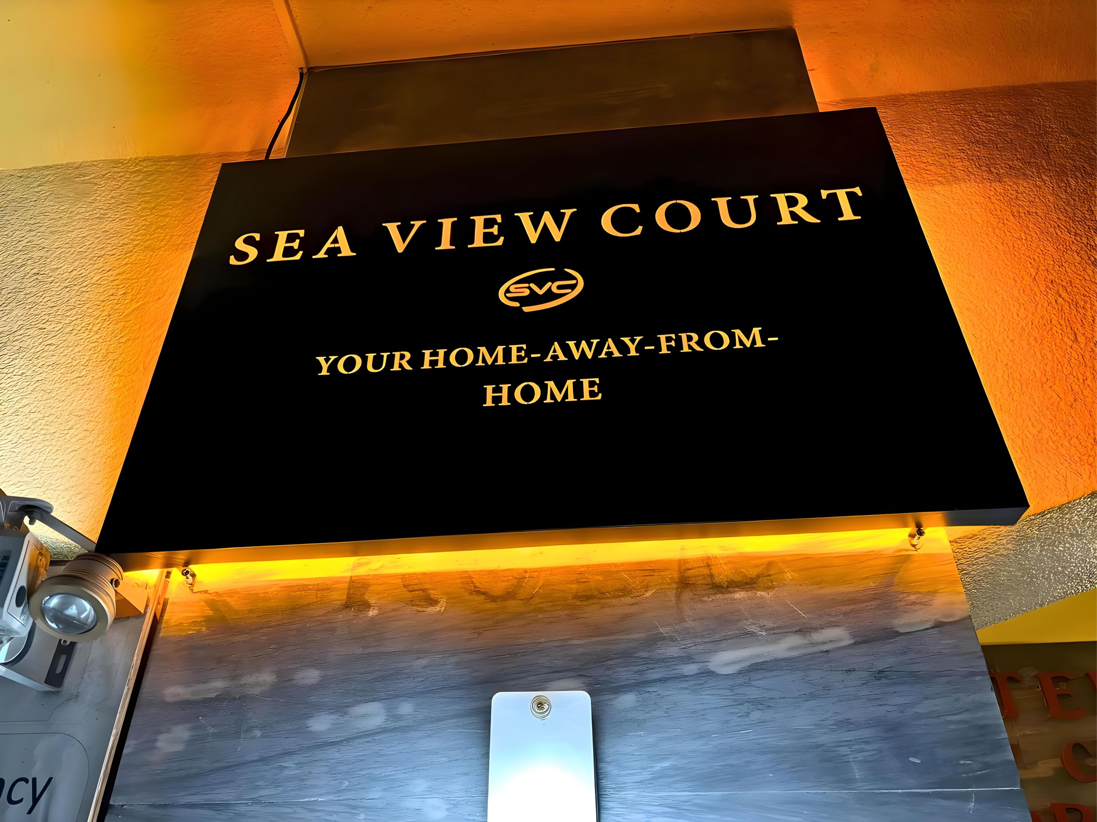 Un letrero que dice "SEA VIEW COURT" con el lema "TU HOGAR FUERA DE CASA".