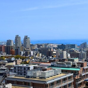 Un paysage urbain avec de hauts immeubles, un mélange de bâtiments résidentiels et commerciaux, et une vue dégagée sur l’océan.