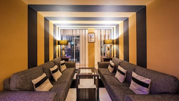 A hotel lobby with a checkered floor, two sofas with patterned upholstery, and two lamps on side tables.