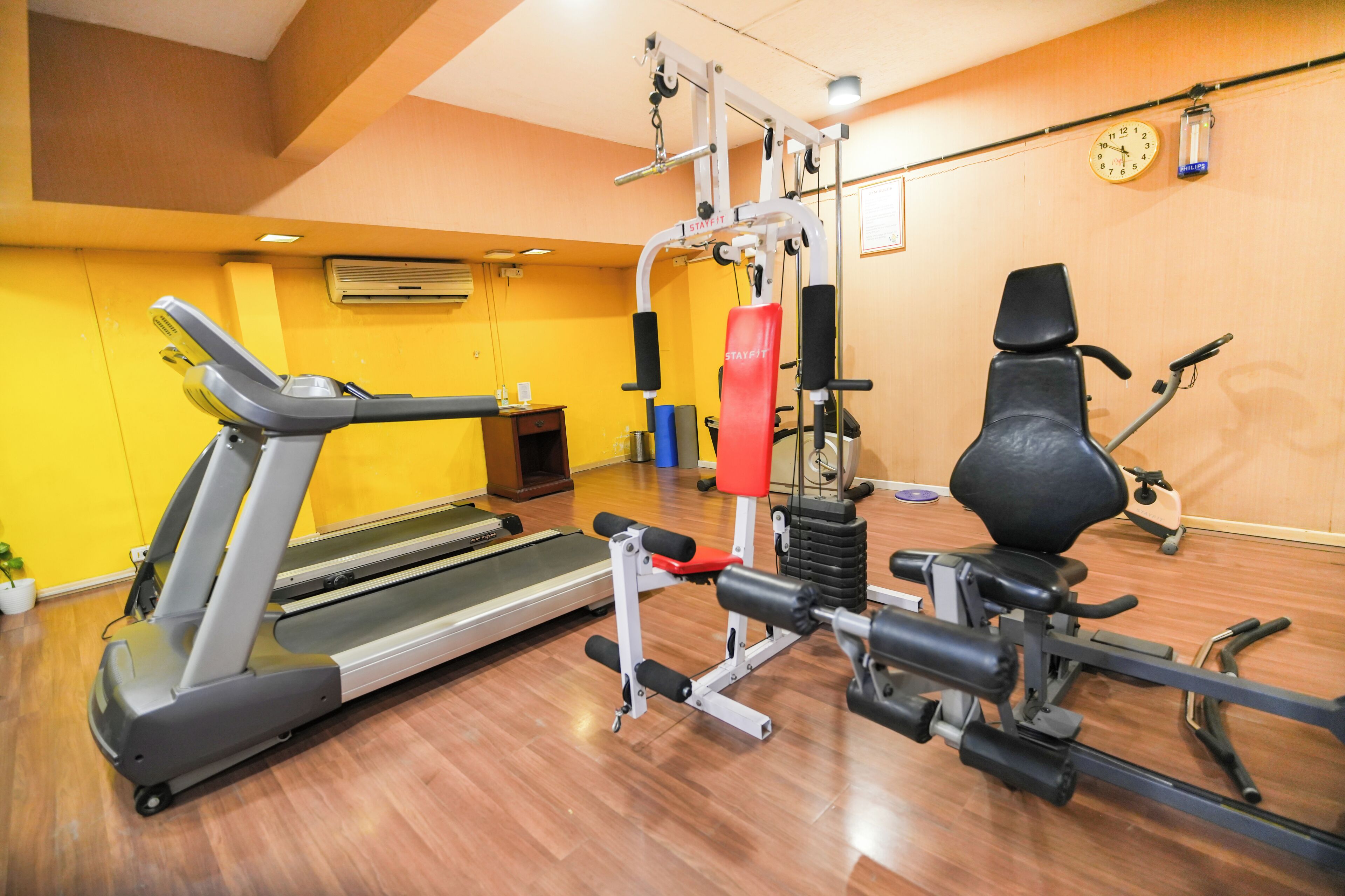 Un gimnasio con cinta de correr, máquinas de pesas y bicicleta estática.