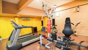 A gym with a treadmill, weight machines, and a stationary bike. - MGM Mark Whitefield (Bengaluru)