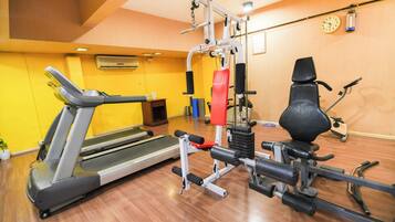 Un gimnasio con cinta de correr, máquinas de pesas y bicicleta estática.