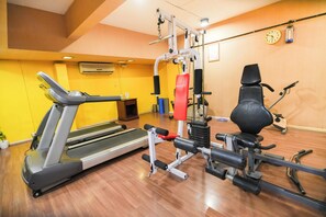 A gym with a treadmill, weight machines, and a stationary bike. - MGM Mark Whitefield (Bengaluru)