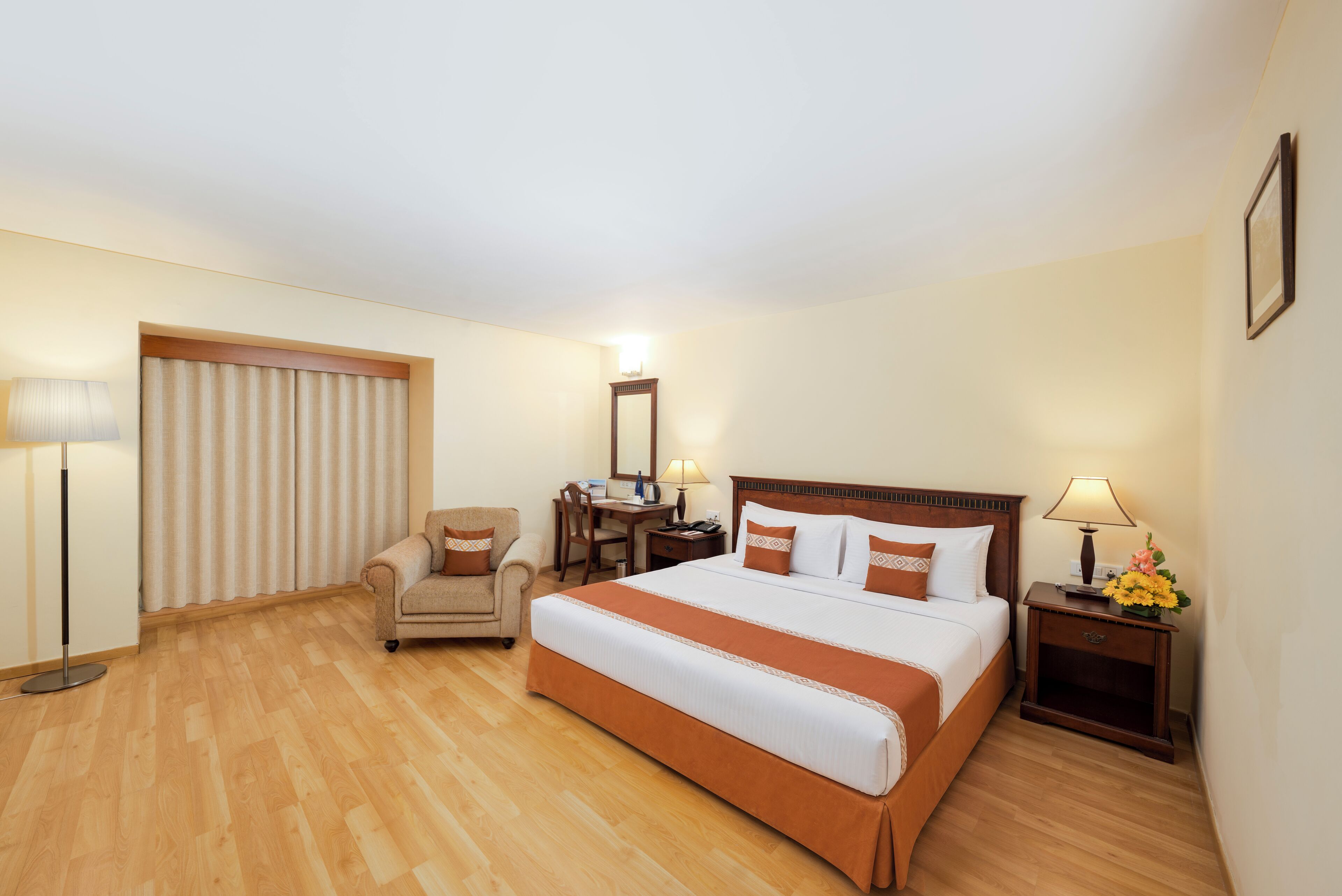 Una habitación de hotel con una cama, una silla, un escritorio, una lámpara y una mesita de noche.