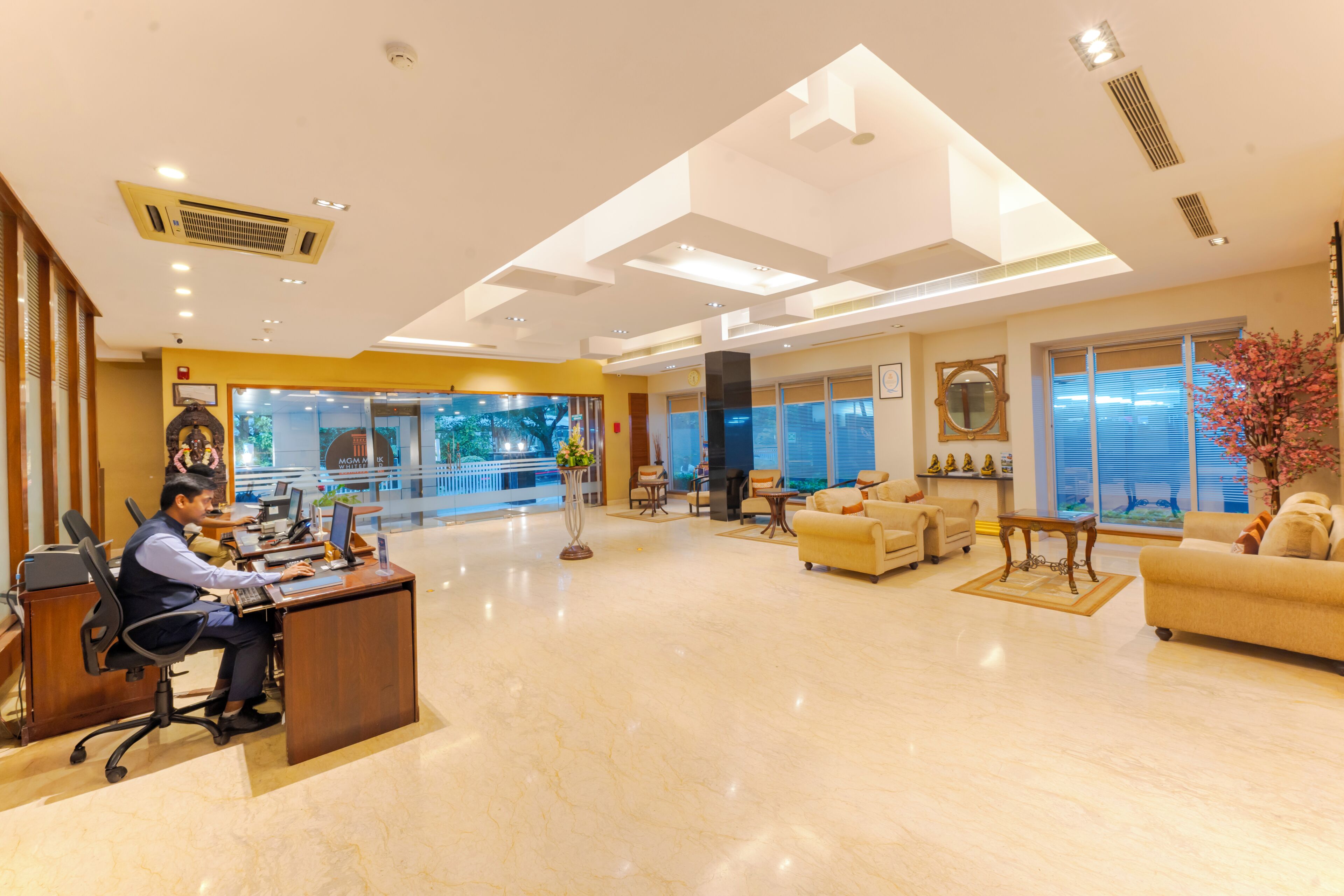 A hotel lobby with a reception desk, seating area, and large windows.
