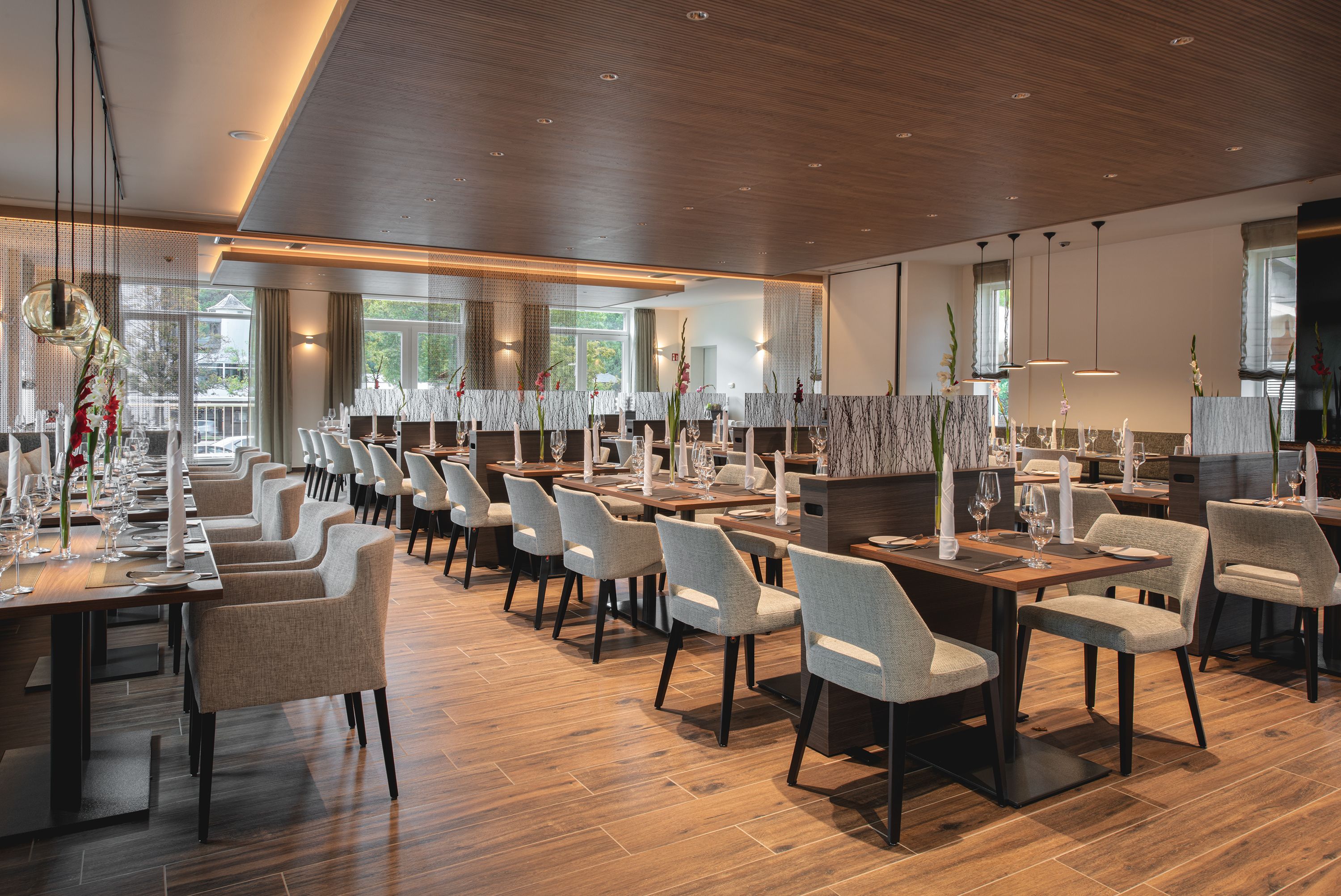 A spacious restaurant with multiple tables and chairs, large windows, and a modern interior design.