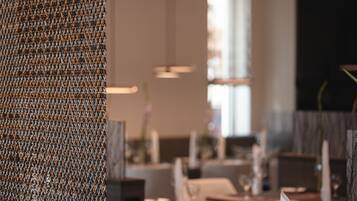 Interior de restaurante com destaque para uma parede texturizada e uma área de refeições desfocada.
