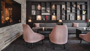 A modern living room with a stone wall, grey sofas, and a built-in bookshelf with decorative items.