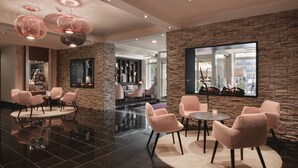 A modern lobby with stone walls, a round table with chairs, and a large window.