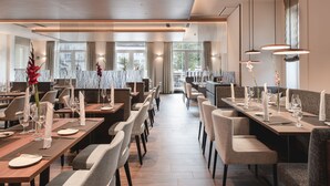 A modern dining area with long tables, chairs, and elegant table settings.