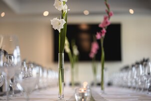 A long dining table with clear glassware and vases with flowers.