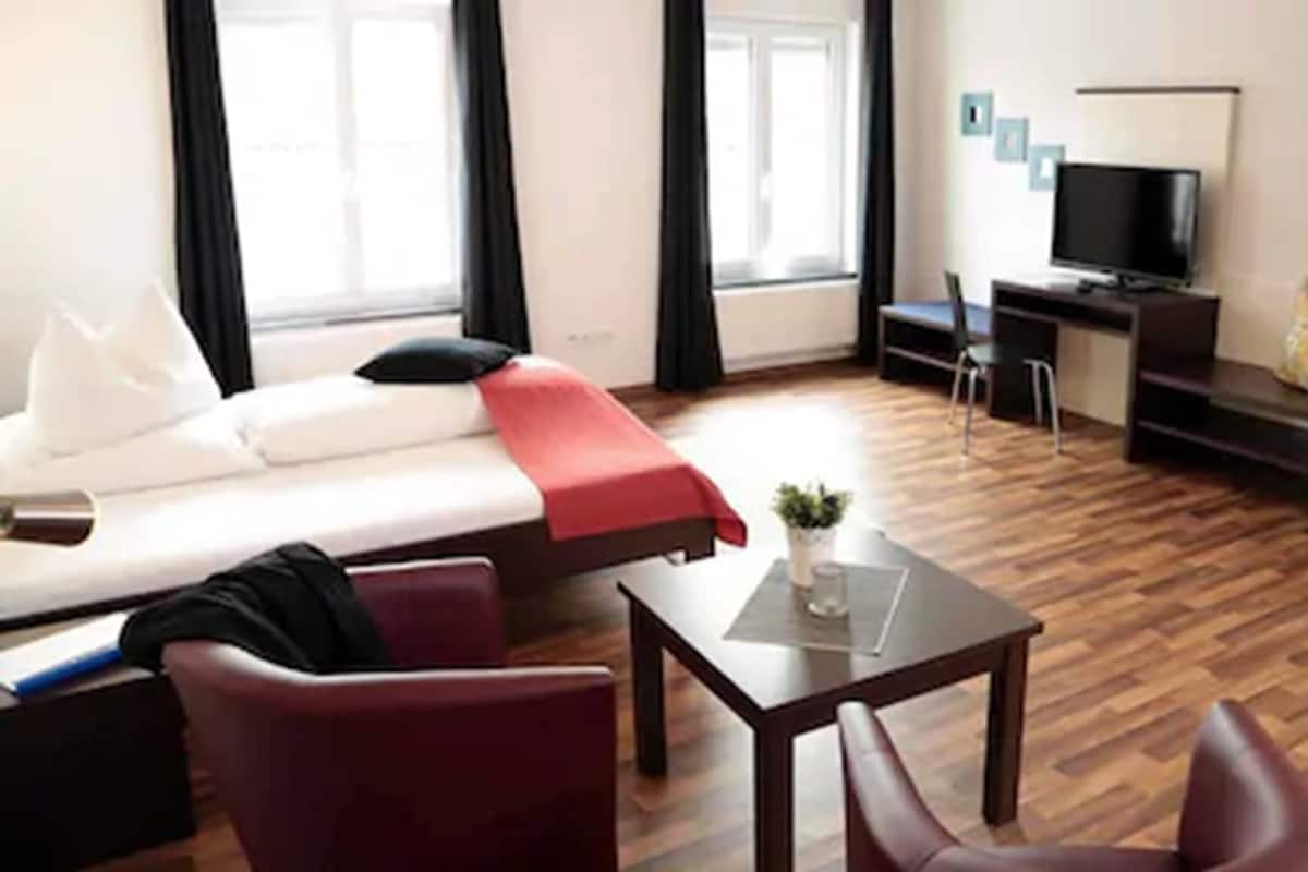 Une chambre d’hôtel avec un lit, un bureau, une télévision et une fenêtre.