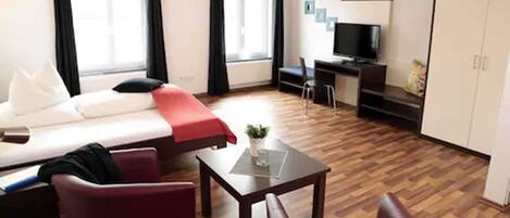 Una habitación de hotel con cama, escritorio, televisión y ventana.