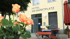 A hotel named "HOTEL AM MARKTPLATZ" with outdoor seating and a potted plant. - Hotel am Marktplatz (Gangkofen)