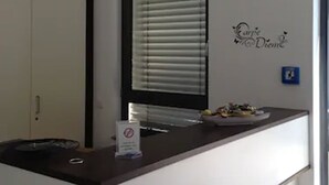 A reception desk with a sign prohibiting smoking, a window with blinds, and a wall decoration. - Hotel am Marktplatz (Gangkofen)