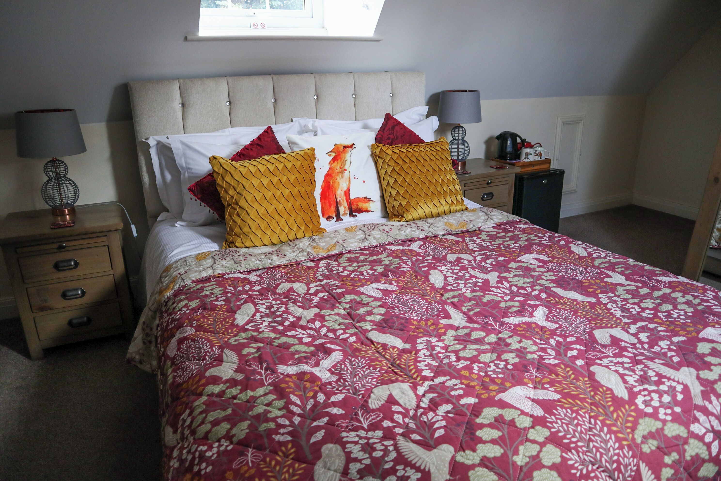 A bedroom with a bed, two bedside tables, a nightstand, a window, and a radiator.