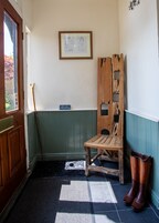 Una habitación con un banco de madera, un bastón y un par de botas.