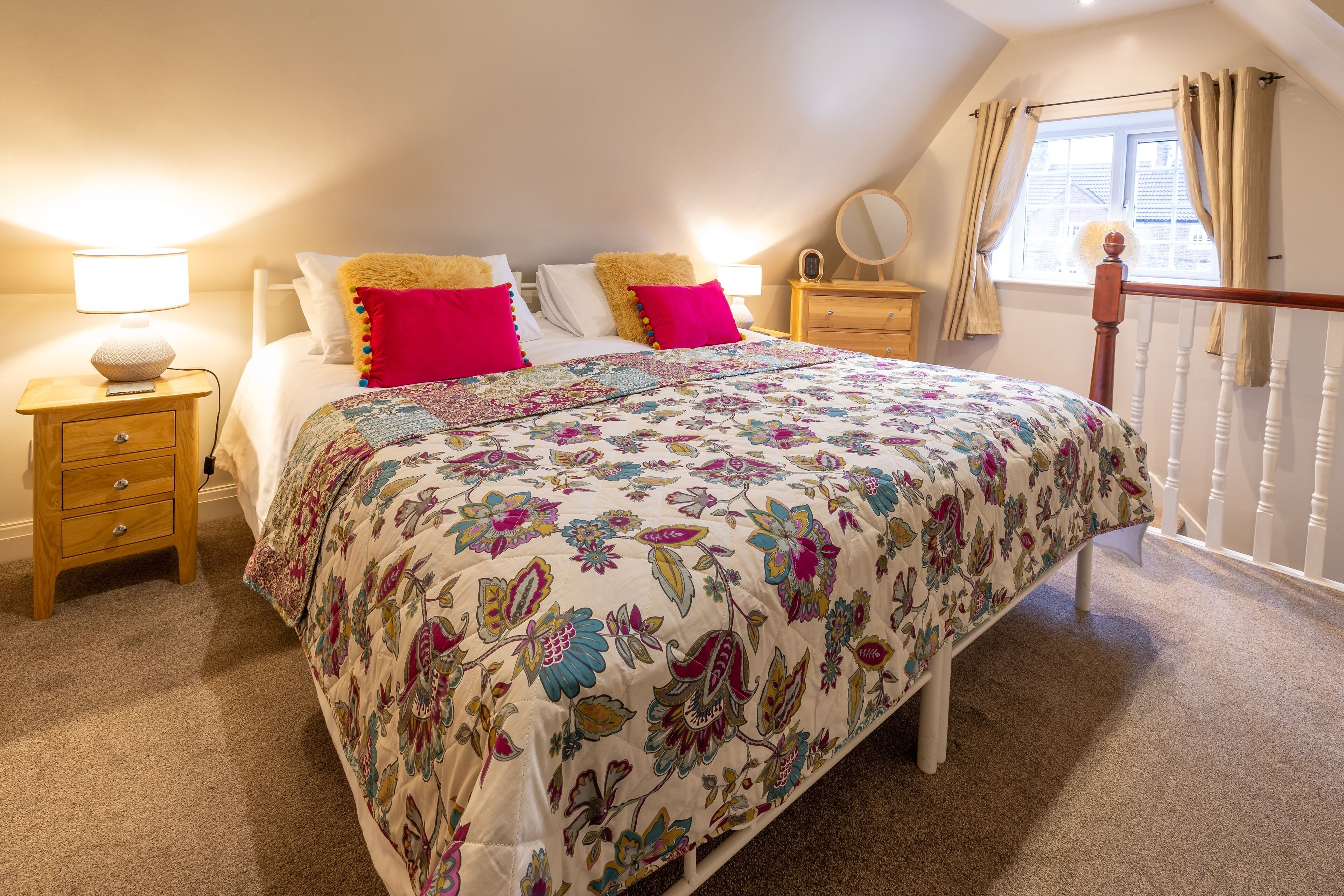 Een slaapkamer met een bed, nachtkastjes, een dressoir, een raam met gordijnen en uitzicht op het exterieur.