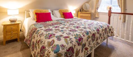 Een slaapkamer met een bed, nachtkastjes, een dressoir, een raam met gordijnen en uitzicht op het exterieur.