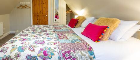 A bedroom with a large bed, a wooden door, and a mirror.