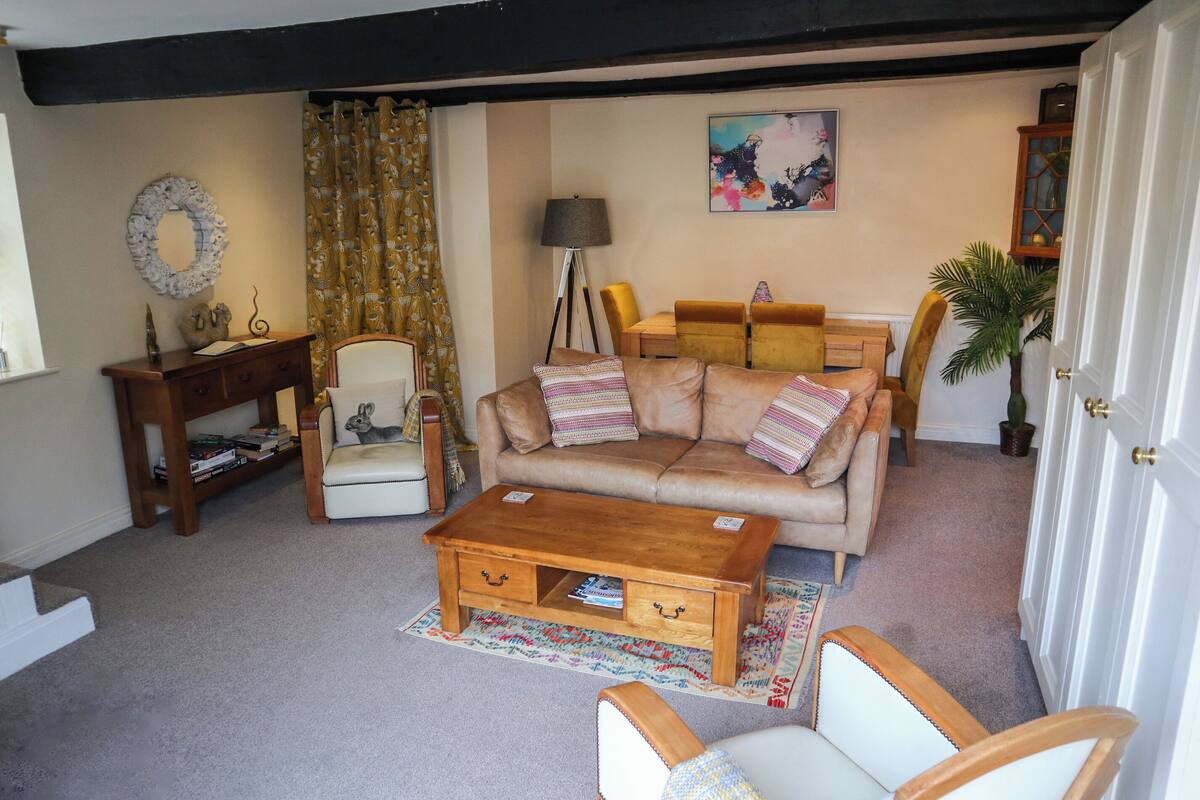 Uma sala de estar aconchegante com sofá, poltronas, mesa de centro, mesa lateral, luminária e um quadro na parede.