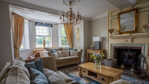 A cozy living room with a sofa set, a wooden coffee table, a fireplace, and a large mirror. - Harmony House (York)
